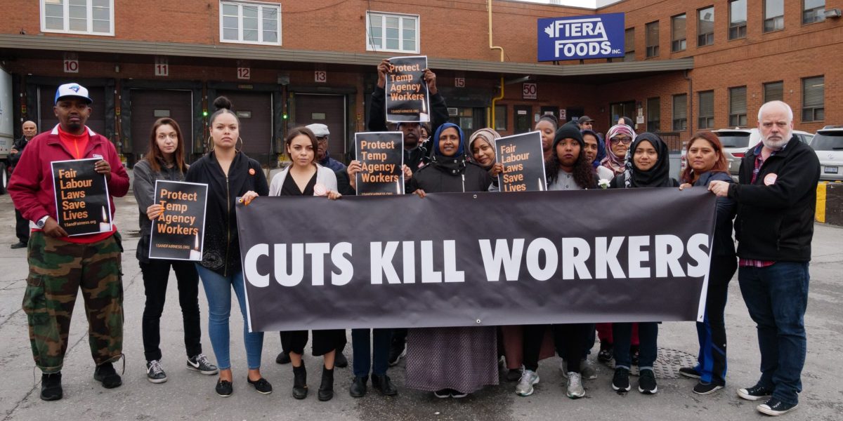 People outside of Fiera foods holding banner that reads Cuts Kill Workers